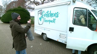 Freddy Radeke vor einem mobilen Unverpackt-Laden mit der Aufschrift "Gretchens Unverpackt".