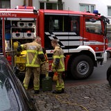 Einsatzkräfte stehen neben einer Pumpe an einem Feuerwehrauto.