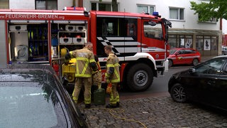 Einsatzkräfte stehen neben einer Pumpe an einem Feuerwehrauto.