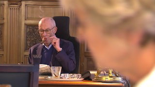 Der verstorbene Uwe Hollweg mit Zigarre im Mund an seinem Schreibtisch im Büro.