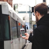 Ein Mann nutzt an einer Straßenbahnhaltestelle in Bremen die VBN "Fahrplaner"-App.