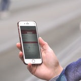 Eine Frau nutzt die VBN-App "Fahrplaner" an einer Straßenbahnhaltestelle.