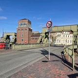 Ein Schild mit der Aufschrift "Brückenschäden" steht vor einer Brücke für Autofahrer.