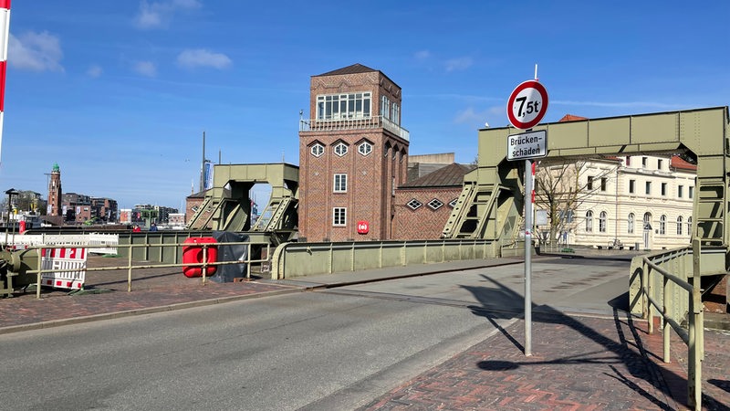 Ein Schild mit der Aufschrift "Brückenschäden" steht vor einer Brücke für Autofahrer.