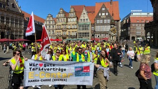 Rund 150 Menschen mit gelben Warnwesten demonstrieren auf dem Marktplatz.