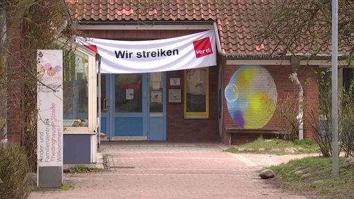 An einem Kinder- und Familienzentrum hängt ein großes Plakat auf dem steht: Wir streiken.