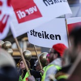Menschen in Warnwesten und mit Verdi-Fahnen streiken