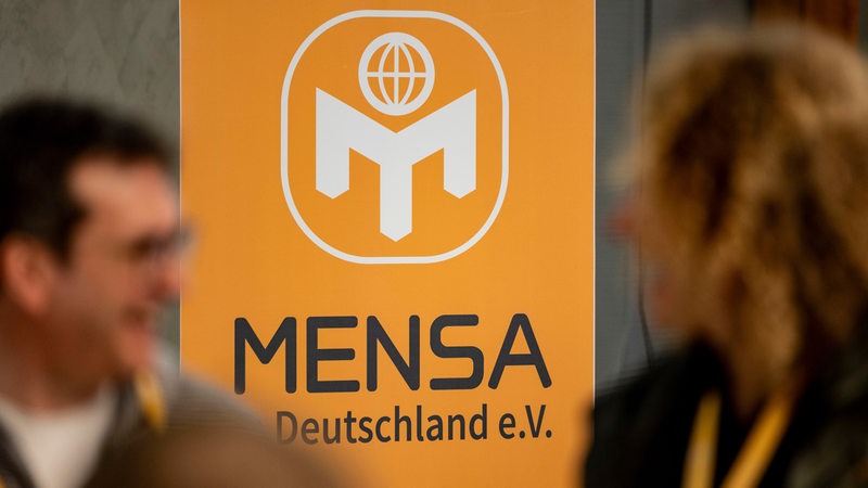 Ein Aufsteller vom Verein Mensa Deutschland e.V. steht in einem Raum.