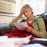 Eine Seniorin blickt sorgenvoll auf eine Rechnung.