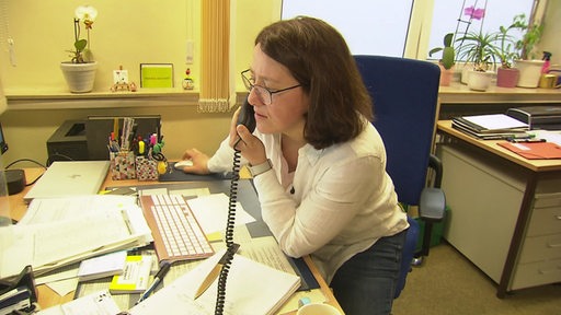 Die Verwaltungskraft Nina Banholzer beim Telefonieren an ihrem Schreibtisch.
