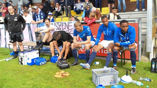 Mehrere Spieler des VfB Oldenburg sitzen niedergeschlagen auf der Ersatzbank.