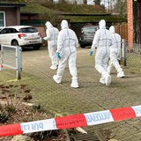 Vier Männer in weißen Ganzkörper-Anzügen gehen auf ein Haus zu