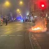 Eine Straße, der rechte Bürgersteig brennt.