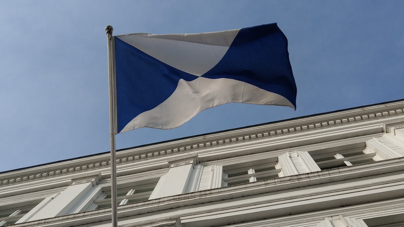 Die blau-weiße Flagge der Reederei weht am Firmengebäude.