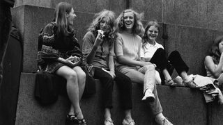 SW-Foto aus den 70er Jahren zeigt jugendliche Mädchen lachend an einem Denkmal sitzend.