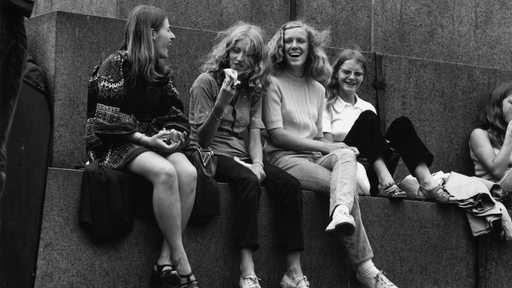 SW-Foto aus den 70er Jahren zeigt jugendliche Mädchen lachend an einem Denkmal sitzend.