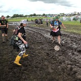 Fans stehen in Wackem im Schlamm und spielen Fußball
