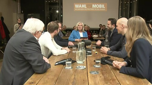 Die Moderatorin Anja Goetz sitzt zwischen Bremer Politikern und spricht mit ihnen über Klimawandel und Mobilität. Im Hintergrund sind Menschen im Publikum zu sehen.