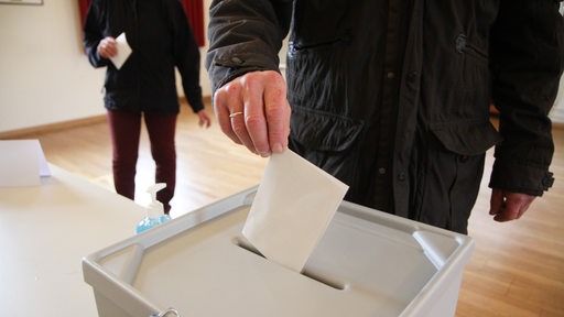 Ein Mann wirft seinen Stimmzettel in eine Wahlurne.