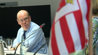 Der Landeswahlleiter Andreas Cors bei der Pressekonferenz, im Vordergrund die Bremer Flagge. 