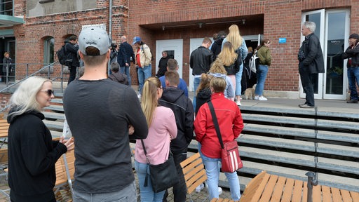 Menschen stehen vor einem Wahllokal in der Schlange.