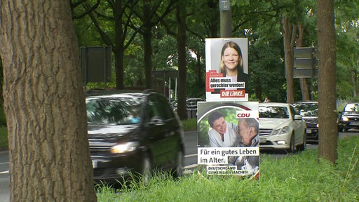 Wahlplakate an einer Säule befestigt, im Hintergrund fahrende Autos.