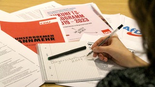 Verschiedene Wahlprogramme liegen auf einem Schreibtisch verteilt.