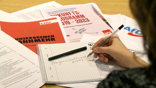 Verschiedene Wahlprogramme liegen auf einem Schreibtisch verteilt.