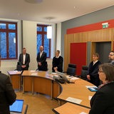 Die Mitglieder des Bremer Wahlprüfungsgericht stehen im Kreis an ihren Tischen.