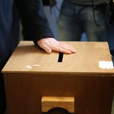 Ein Mann legt seine Hand auf den Schlitz einer Wahlurne (Archivbild)