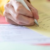 Nahaufnahme einer Hand mit Stift beim Ausfüllen des Wahlzettels