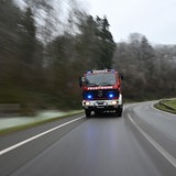 Ein Feuerwehrauto fährt durch ein Waldgebiet.