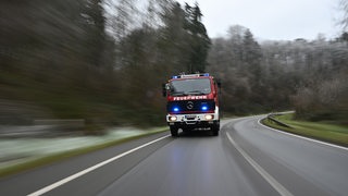 Ein Feuerwehrauto fährt durch ein Waldgebiet.