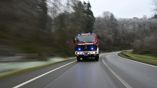 Ein Feuerwehrauto fährt durch ein Waldgebiet.