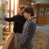 Zwei Schülerinnen schauen auf eine Glasvitrine.
