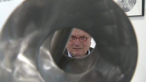 Mann schaut durch eine Skulptur
