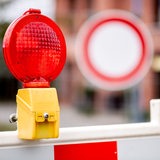 Eine rote Warnleuchte hängt an einer Baustelle vor einem Verkehrsschild, das auf die verbotene Durchfahrt für Fahrzeuge aller Art hinweist. 
