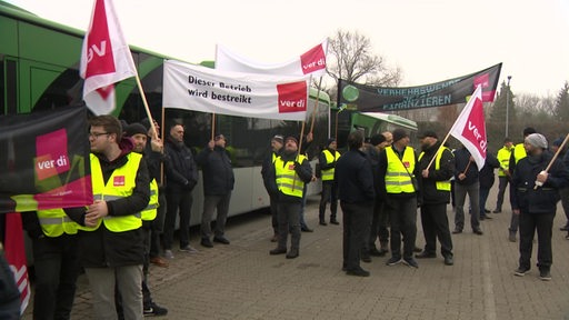 Zu sehen sind streikende Mitarbeiter der Bahn, welche Plakate und Banner in die halten.