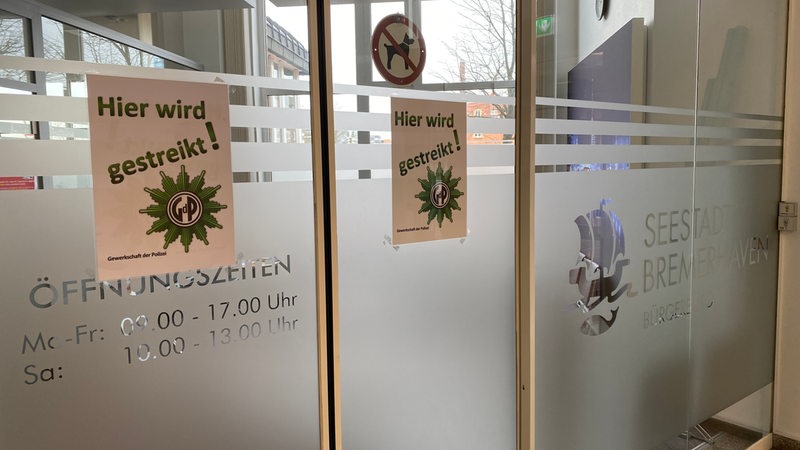 An einer Fensterscheibe hängen Zettel mit der Aufschrift "Hier wird gestreikt".