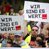 Streik-Teilnehmer halten Schilder hoch mit der Aufschrift "Wir sind es wert".