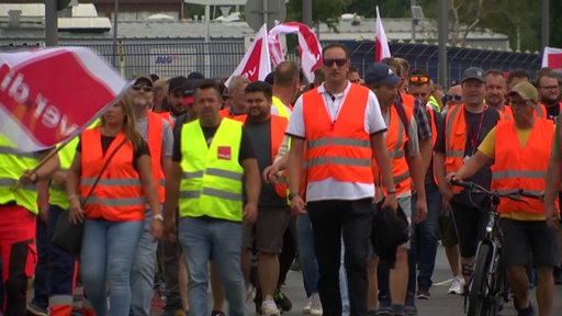Mehrere Hafenarbeiter in bunten Warnwesten streiken in Bremerhaven.