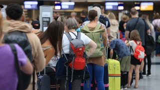 Reisende stehen an einem Flughafen in einer langen Warteschlange.