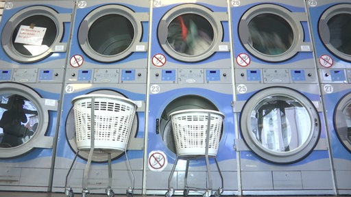 Viele Waschmaschinen, ein paar davon gefüllt mit Wäsche.