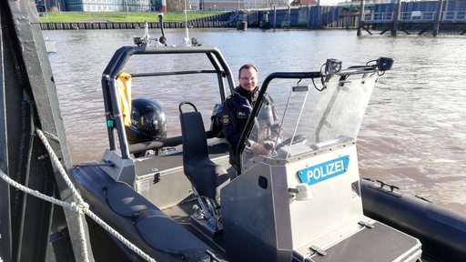 Ein Mann ist auf einem Polizei Schlauchboot auf dem Wasser zu sehen