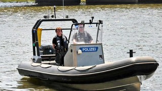 Die Wasserschutzpolizei in einem Motorboot mit der Aufschrift "Polizei" auf Streife auf dem Wasser.
