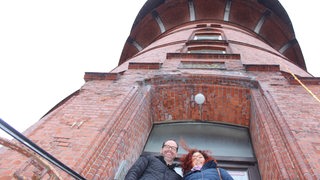 Ein Mann und eine Frau stehen vor einem Turm.