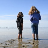 Zwei Mädchen sind Barfuß im Wattenmeer unterwegs und genießen das Wetter.