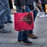 Ein Passant trägt eine weihnachtliche Tüte des Kaufhauses Galeria über die Frankfurter Einkaufsmeile Zeil.