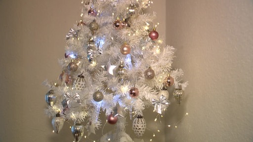 Ein künstlicher, weißer Weihnachtsbaum, der kitschig geschmückt wurde.