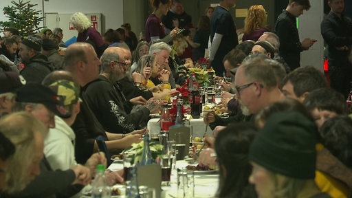 Mehrere Personen essen und trinken an einem langen Tisch.